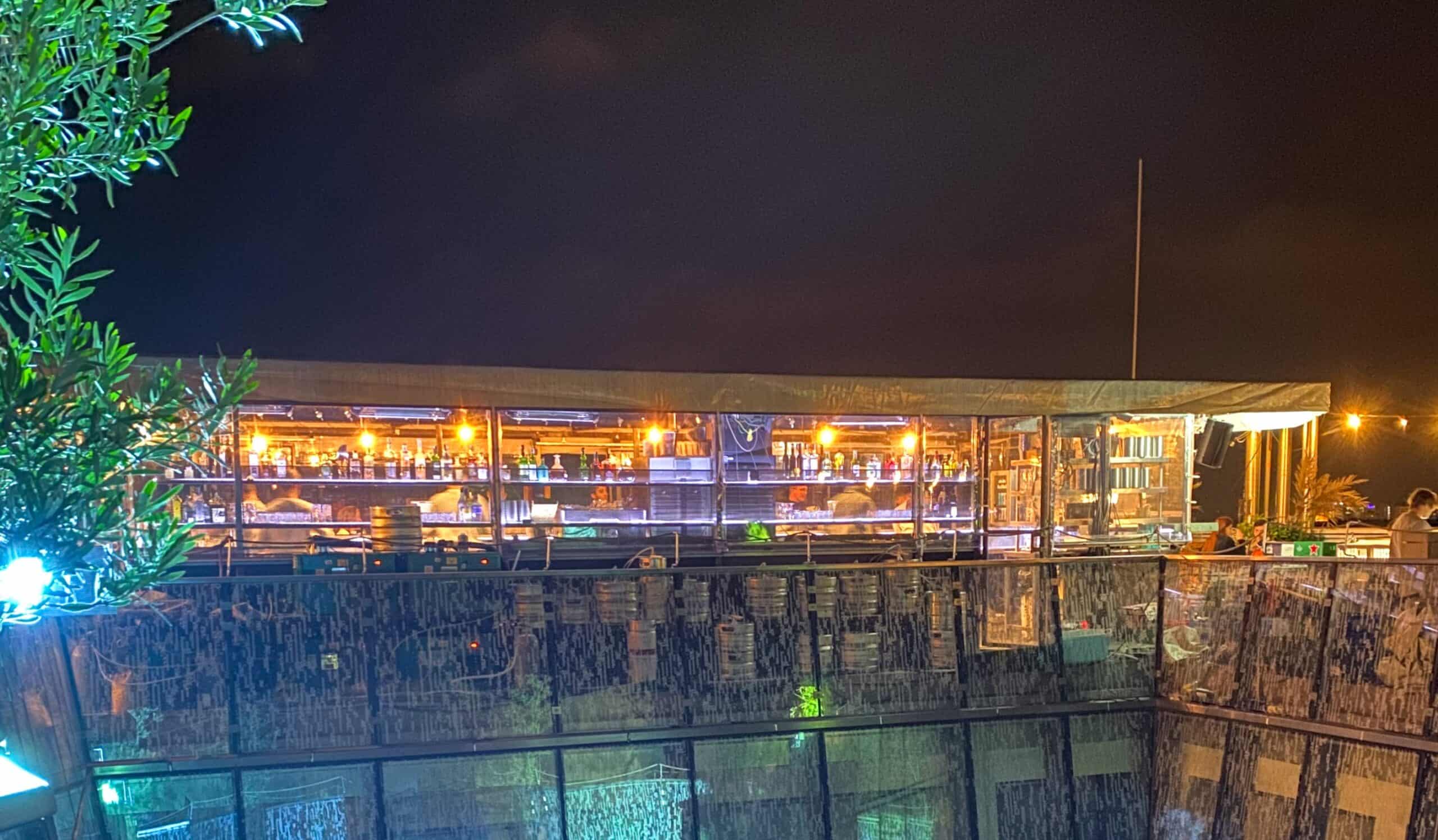 The lively atmosphere of the 360 Bar at night, offering a panoramic view of Budapest's horizon from above.