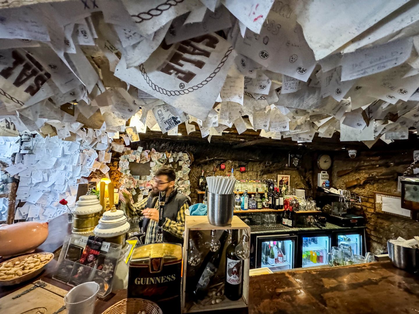 View of the bar area in the For Sale Pub covered with paper notes and flyers left behind by customers