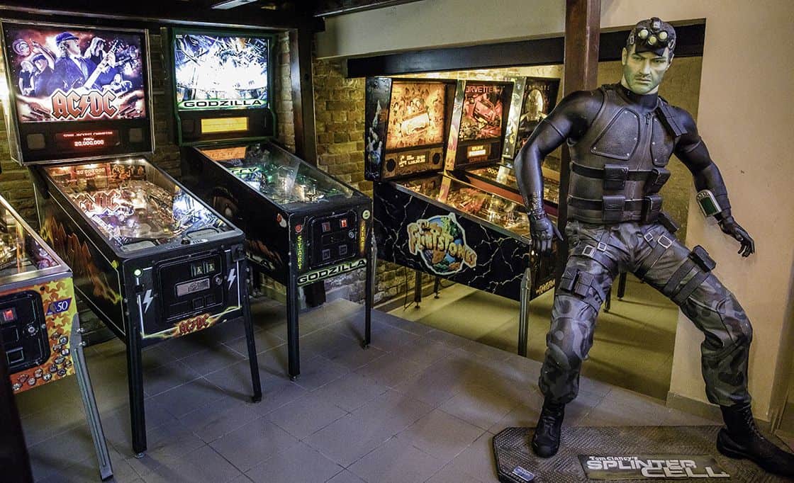 An AC/DC and Godzilla pinball machine next to a life-sized video game character statue