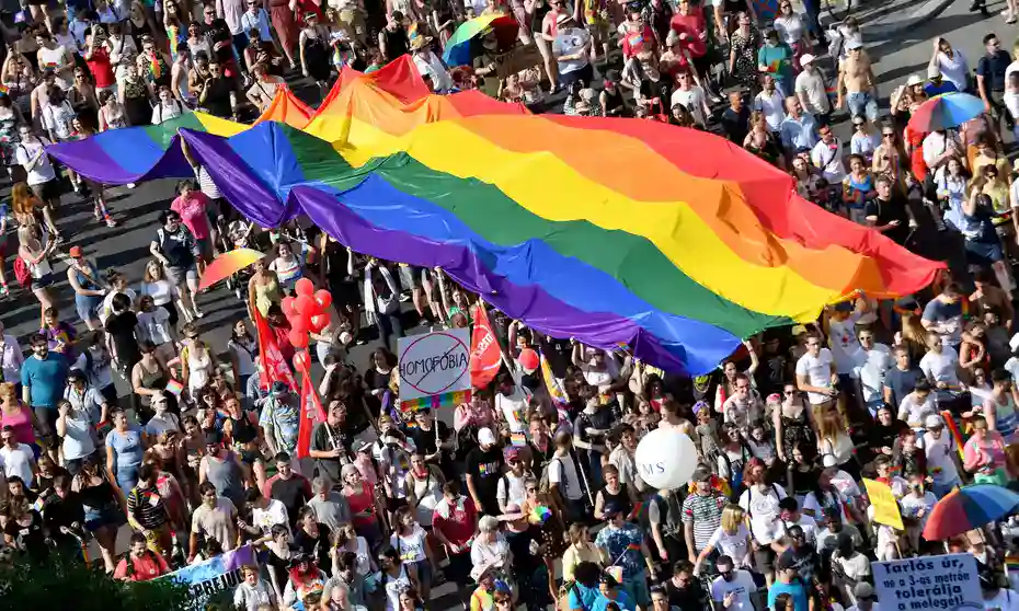Aerial view of participants carrying a massive, elongated rainbow flag during a march
