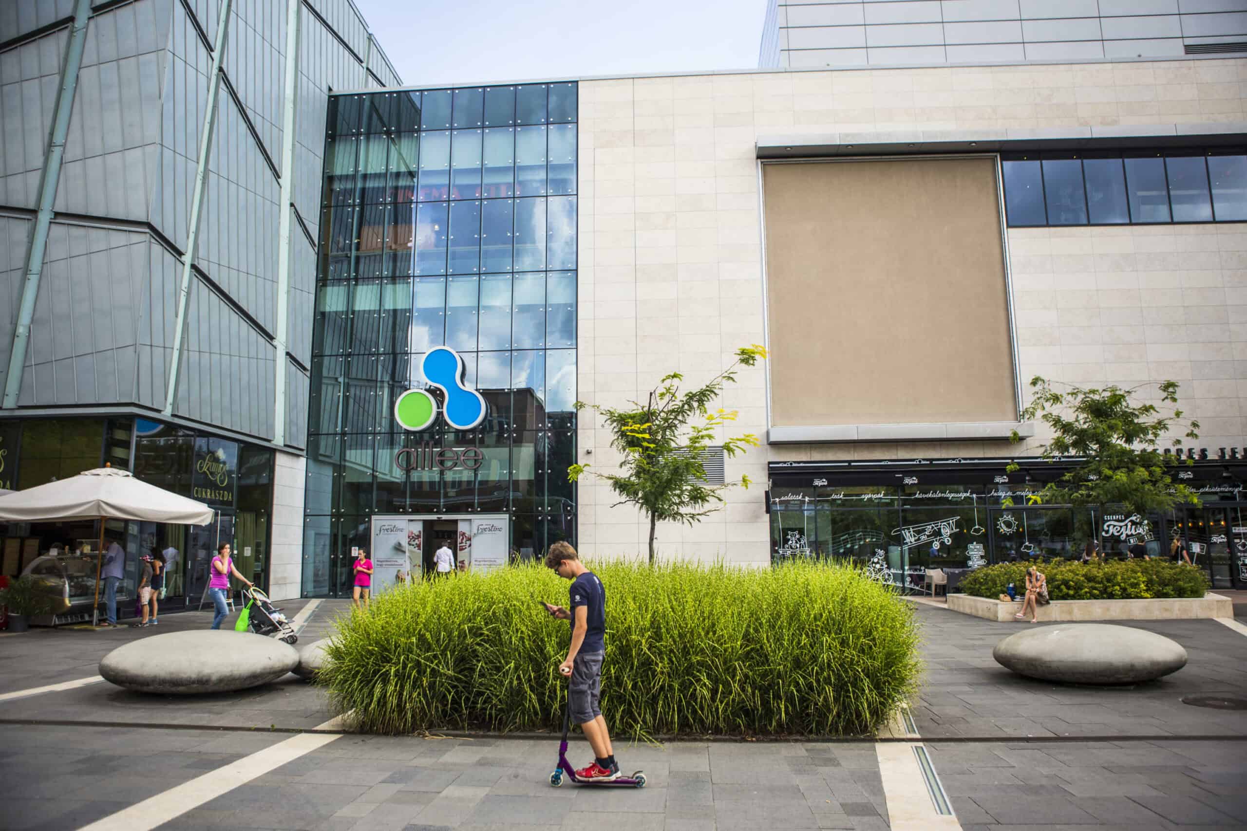 The main entrance and modern glass facade of Allee Mall in Budapest