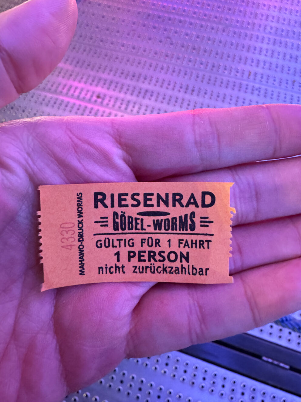 A brightly colored paper entry wristband worn on a visitor's wrist