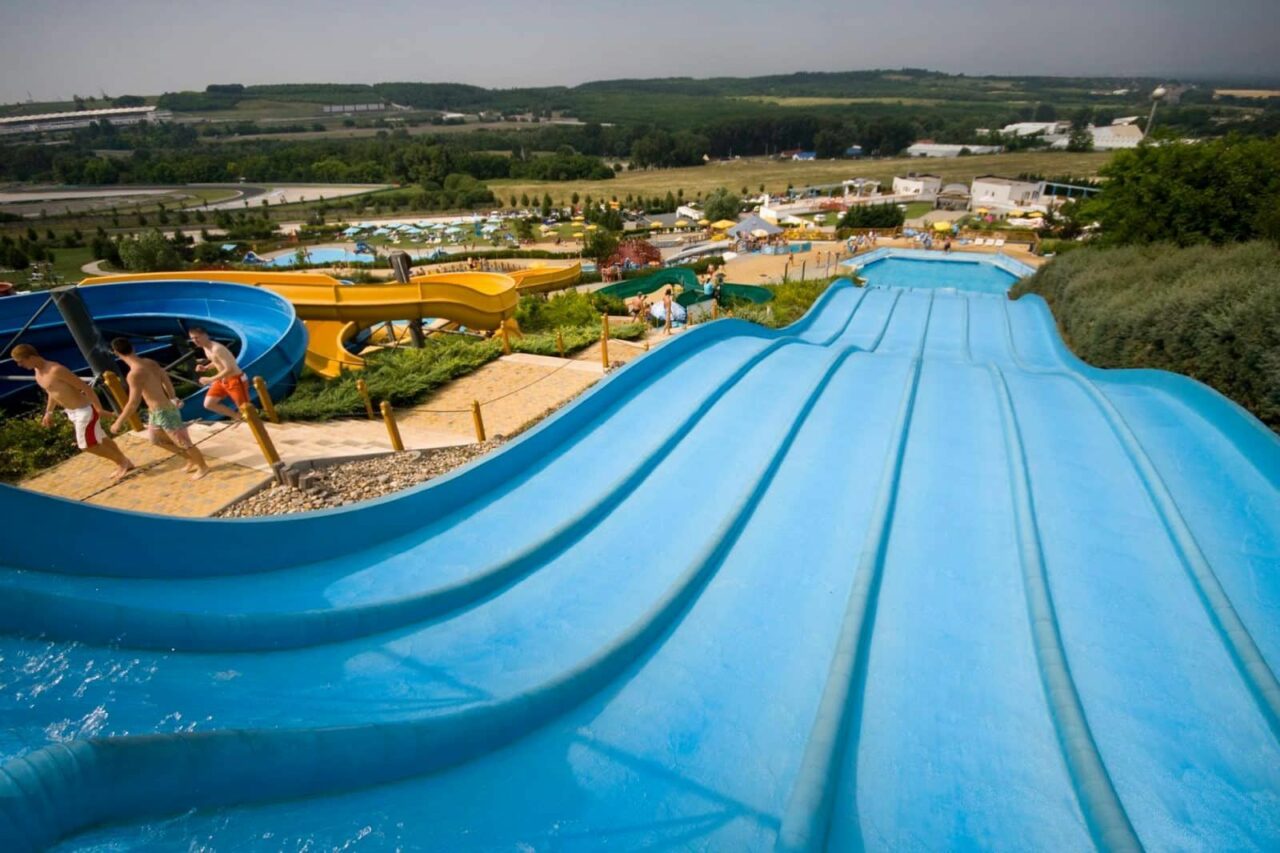 A massive multi-lane blue water slide plunging down a hill at Aquarena