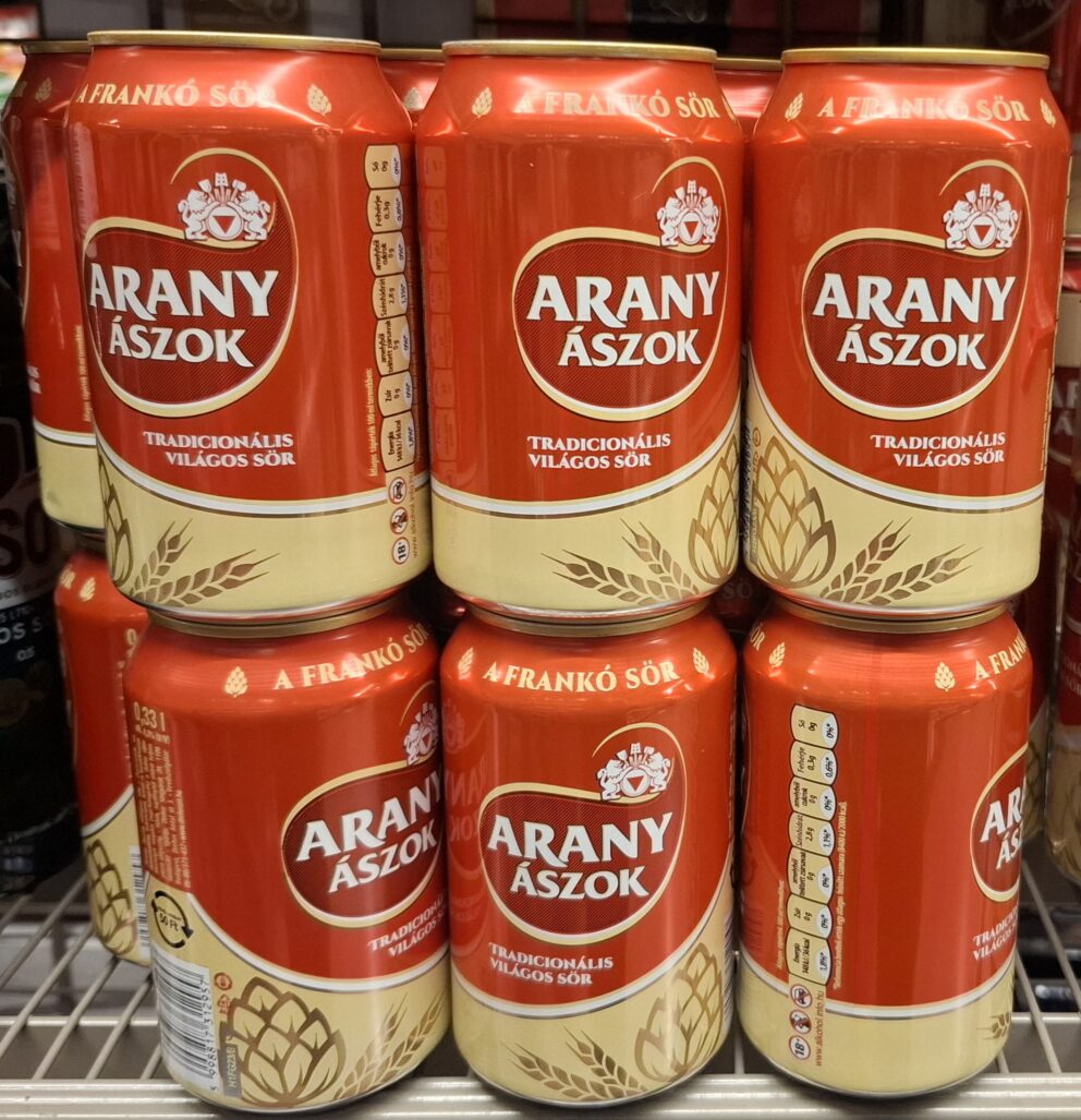 A poured glass and a gold-and-white can of Arany Ászok light lager beer
