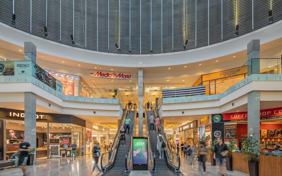 Interior view of the multi-level Arena Mall with shops and escalators