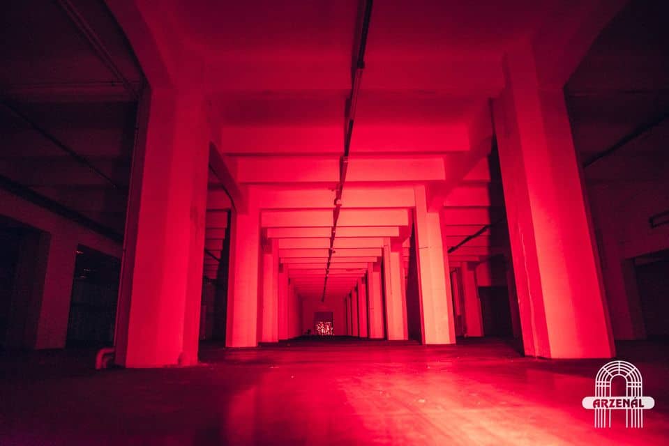 The raw industrial warehouse interior of Arzenal club bathed in red light