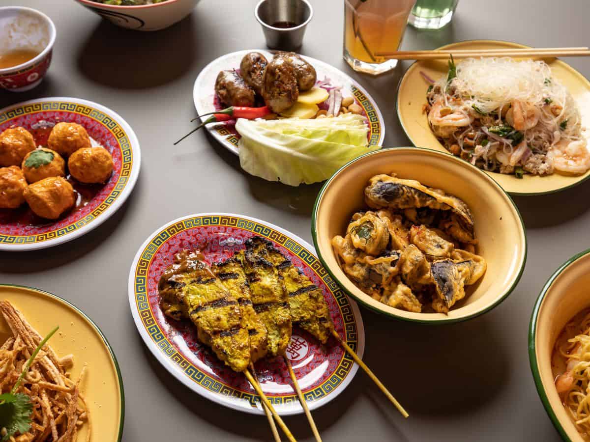 A vibrant feast of Thai street food dishes on retro enamel plates