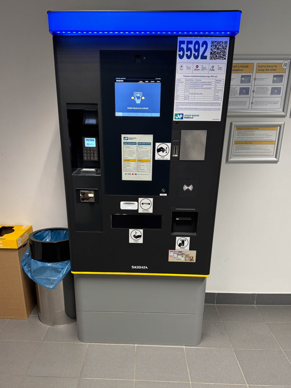 A modern black automated parking payment machine inside a garage