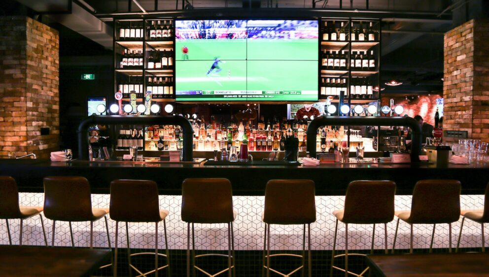 A modern sports bar interior with multiple screens showing live sports matches