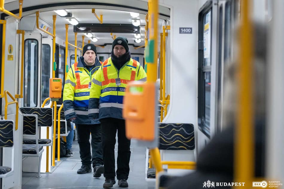 Security guards in high-visibility jackets walking inside a tram