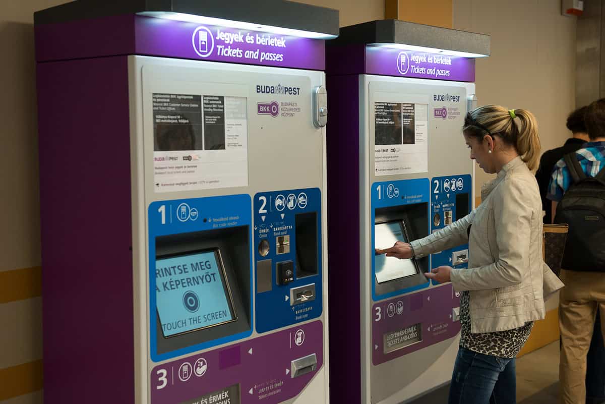 A passenger using the purple BKK ticket machine to buy 100E shuttle tickets at Budapest Airport