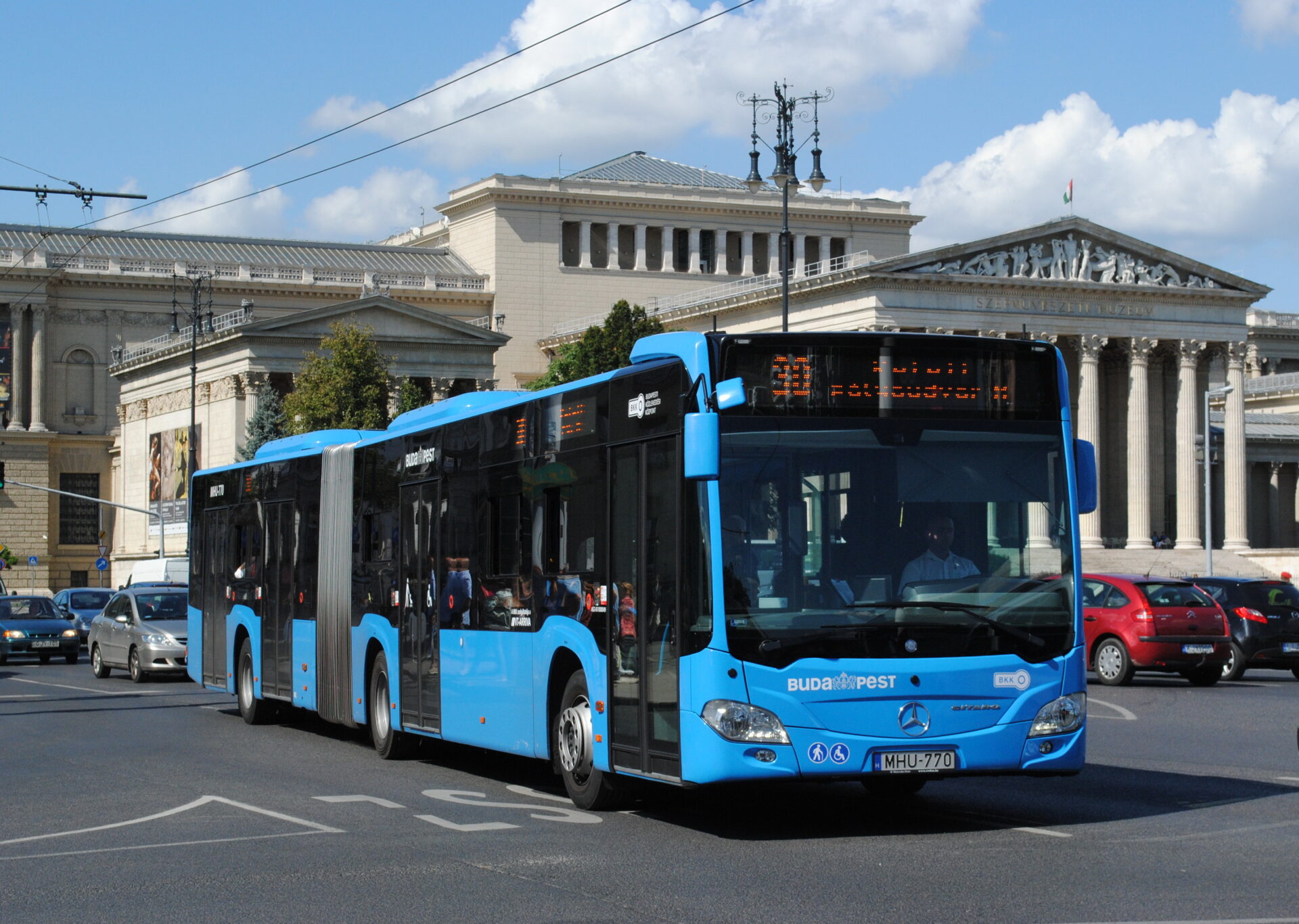 A modern articulated blue BKK bus traveling on a Budapest street