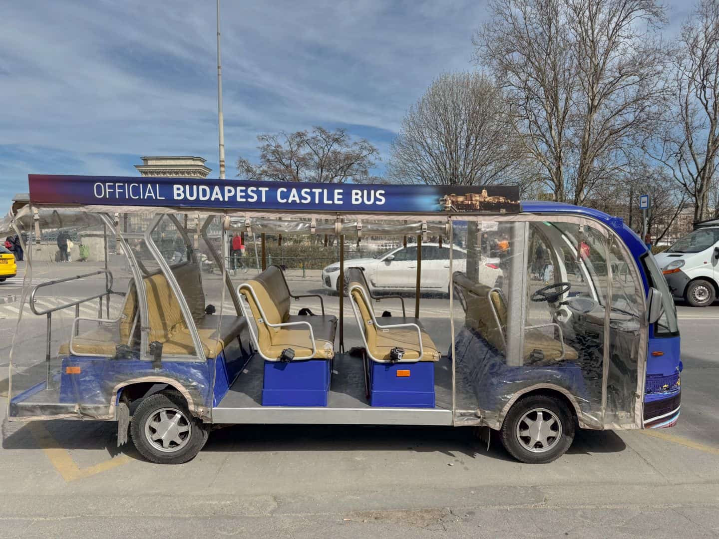 A small public transport bus navigating the narrow streets of the Buda Castle District
