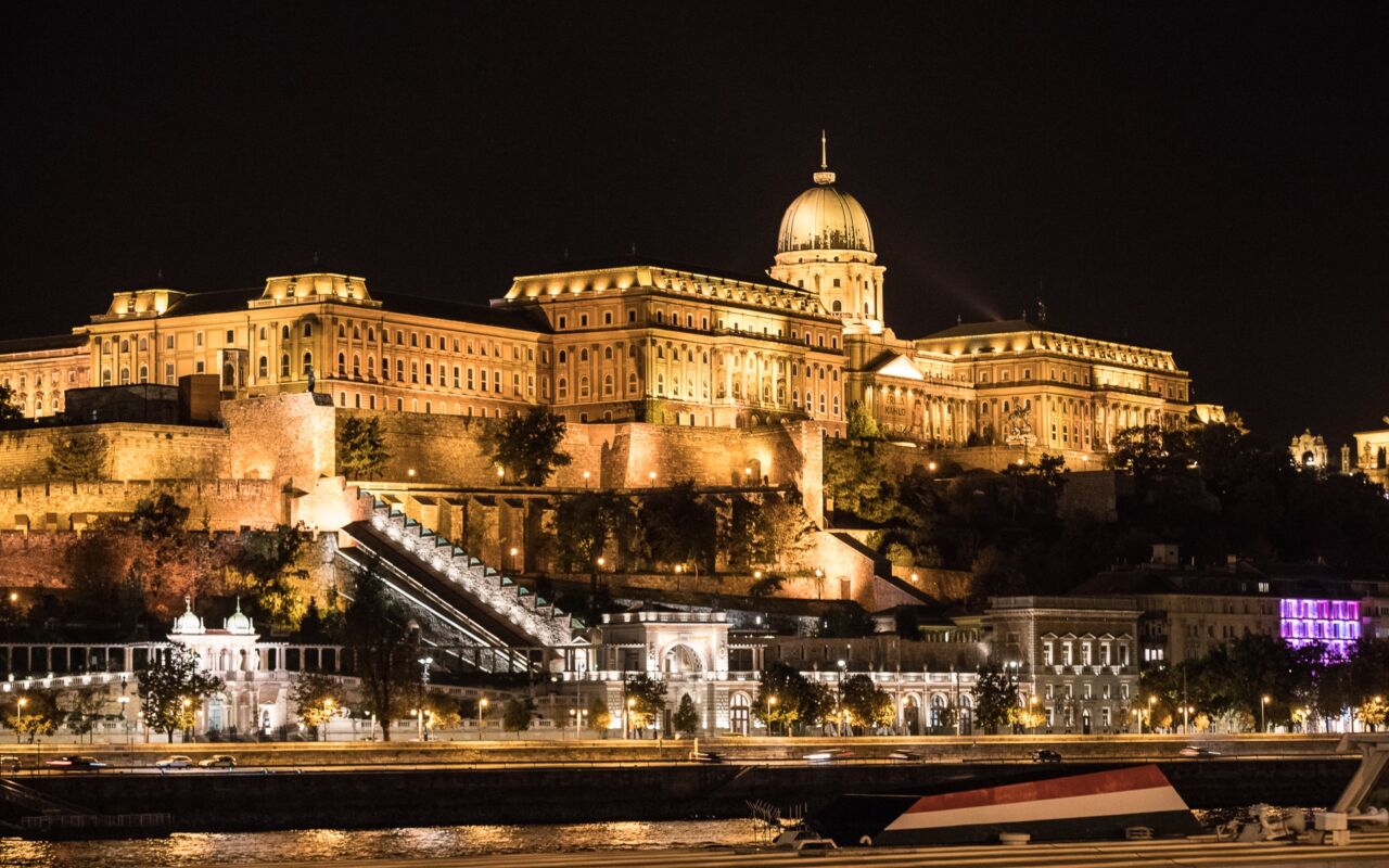 The majestic Buda Castle complex illuminated at night, overlooking the glowing Danube River