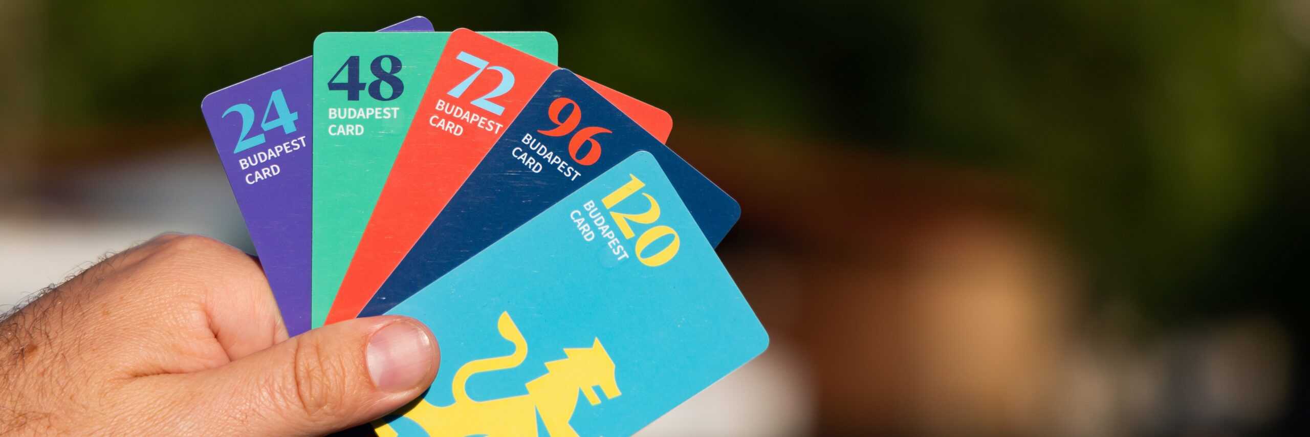 A person holding various versions of the official Budapest Card city pass