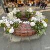 A decorative brick planter filled with white flowers on a cobblestone street in the Jewish Quarter