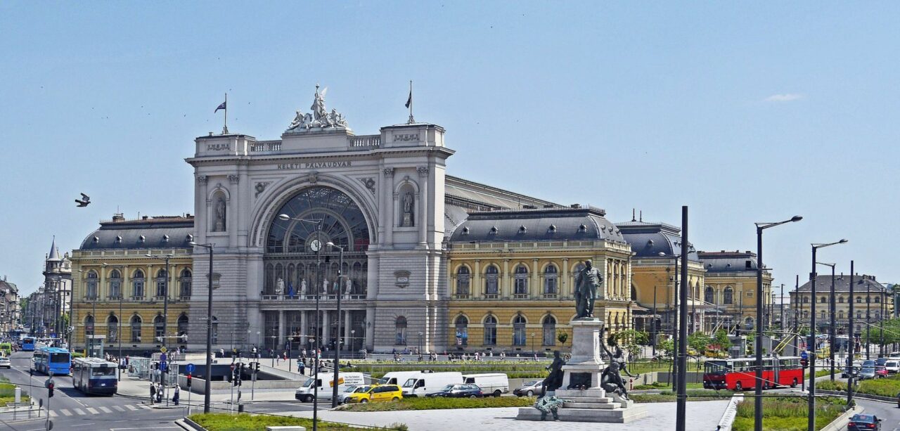 The grand illuminated neoclassical facade of Keleti Train Station at twilight