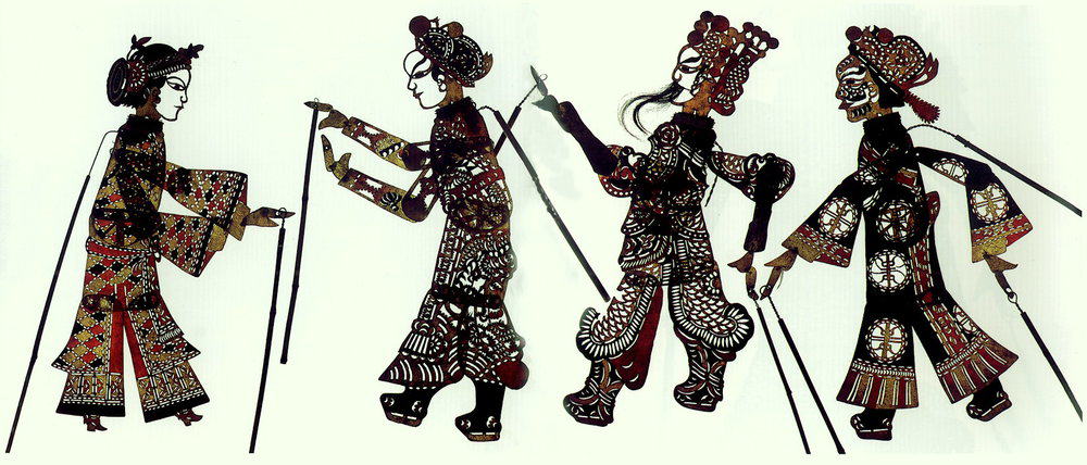 Intricate traditional shadow puppets against a white illuminated background