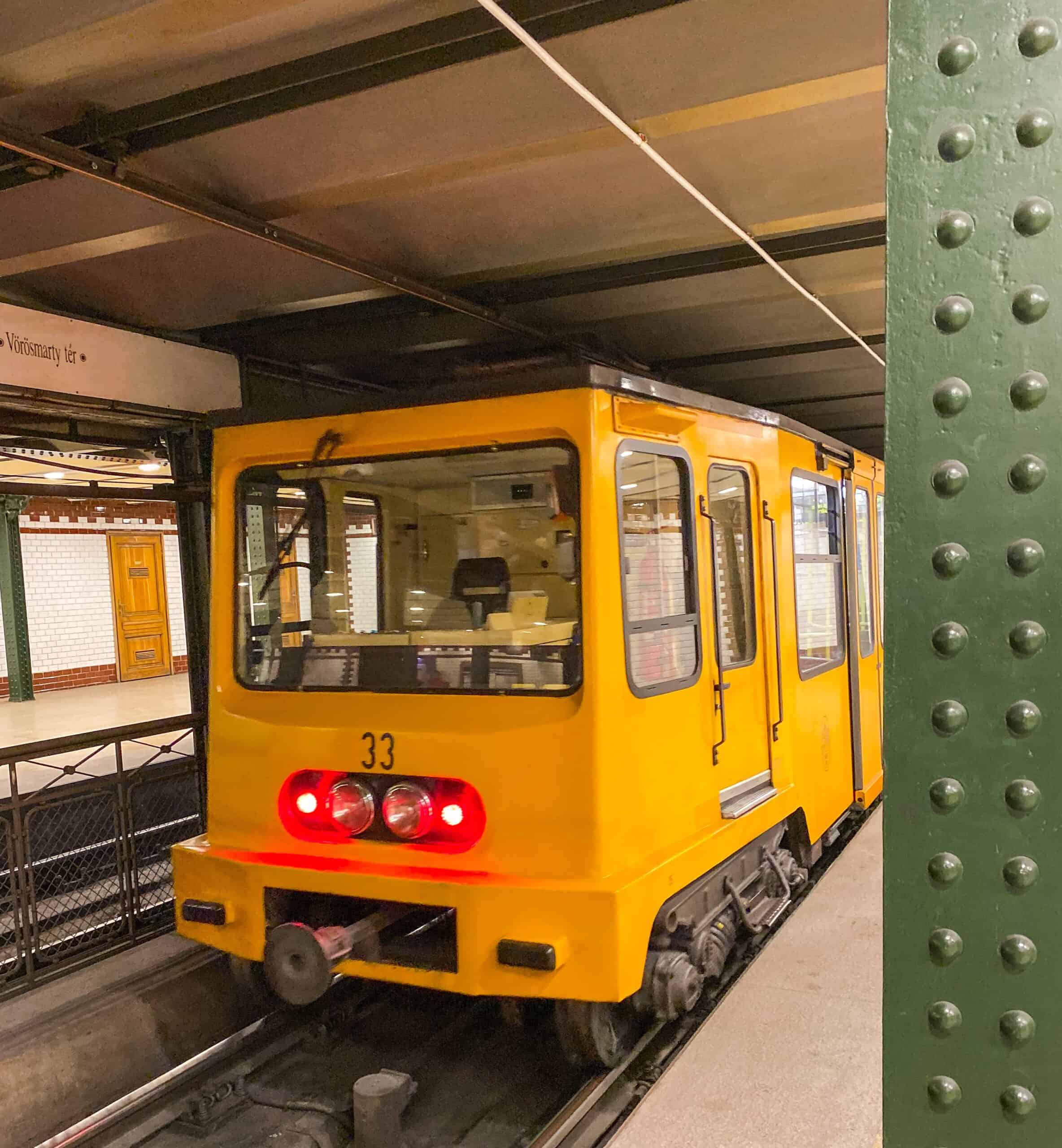 A classic yellow car of the Budapest Metro Line M1, the oldest underground in continental Europe, at a station.