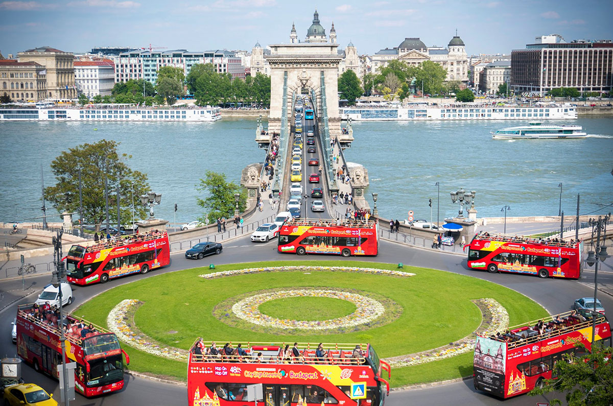 Red double-decker hop-on hop-off tour buses in front of the Chain Bridge in Budapest