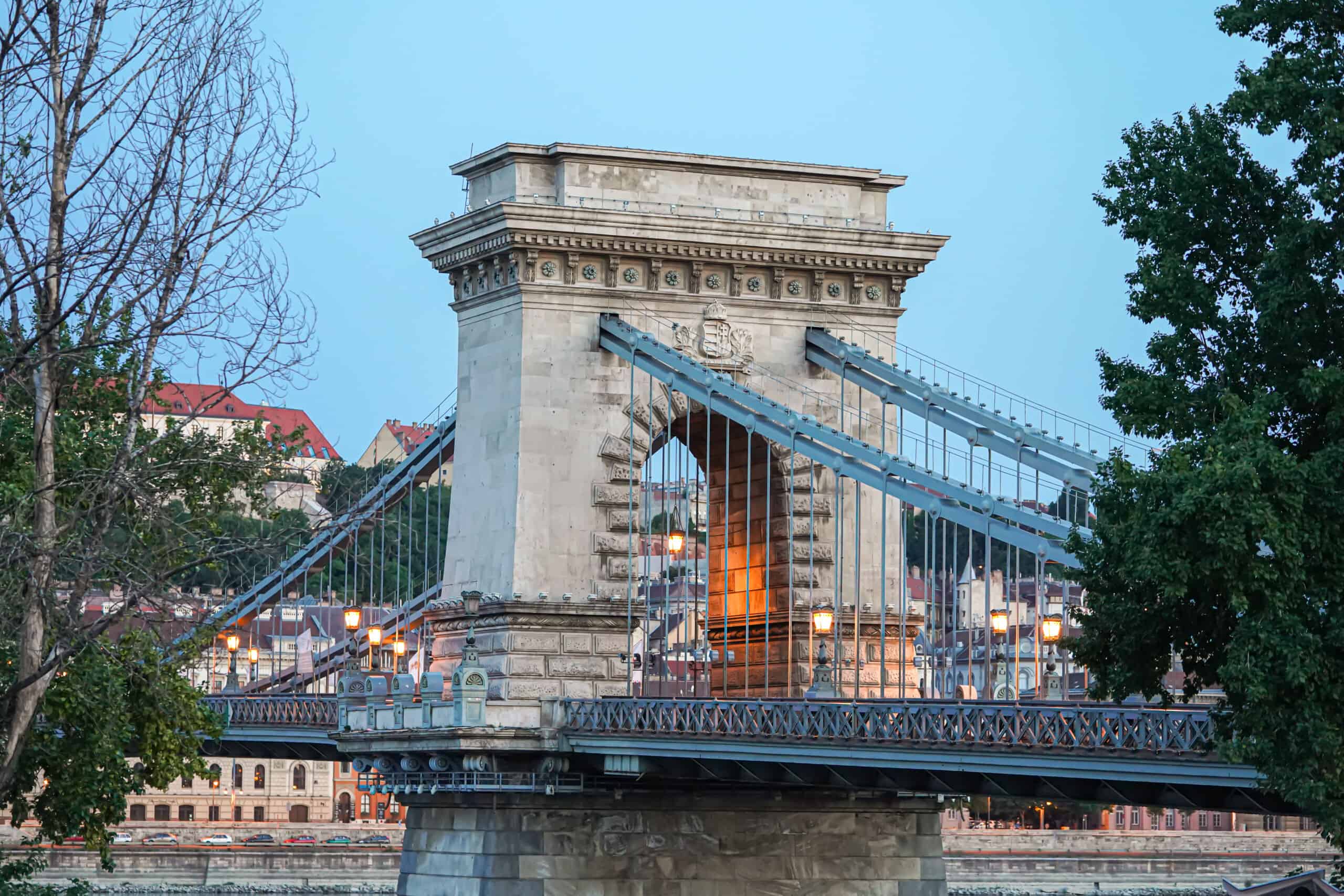 The elegant iron suspension chains and stone arches of the bridge by day