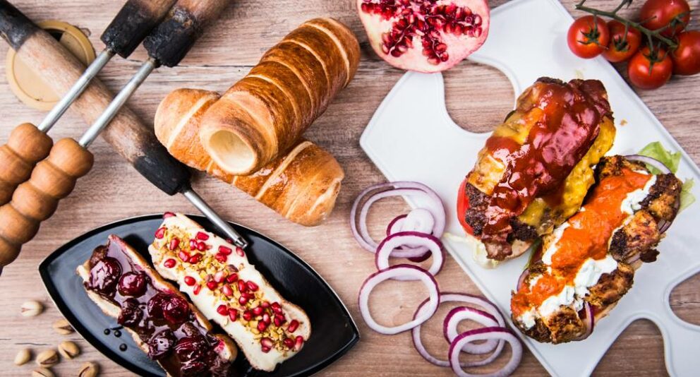 An array of sweet and savory chimney cake creations including meat-filled burgers