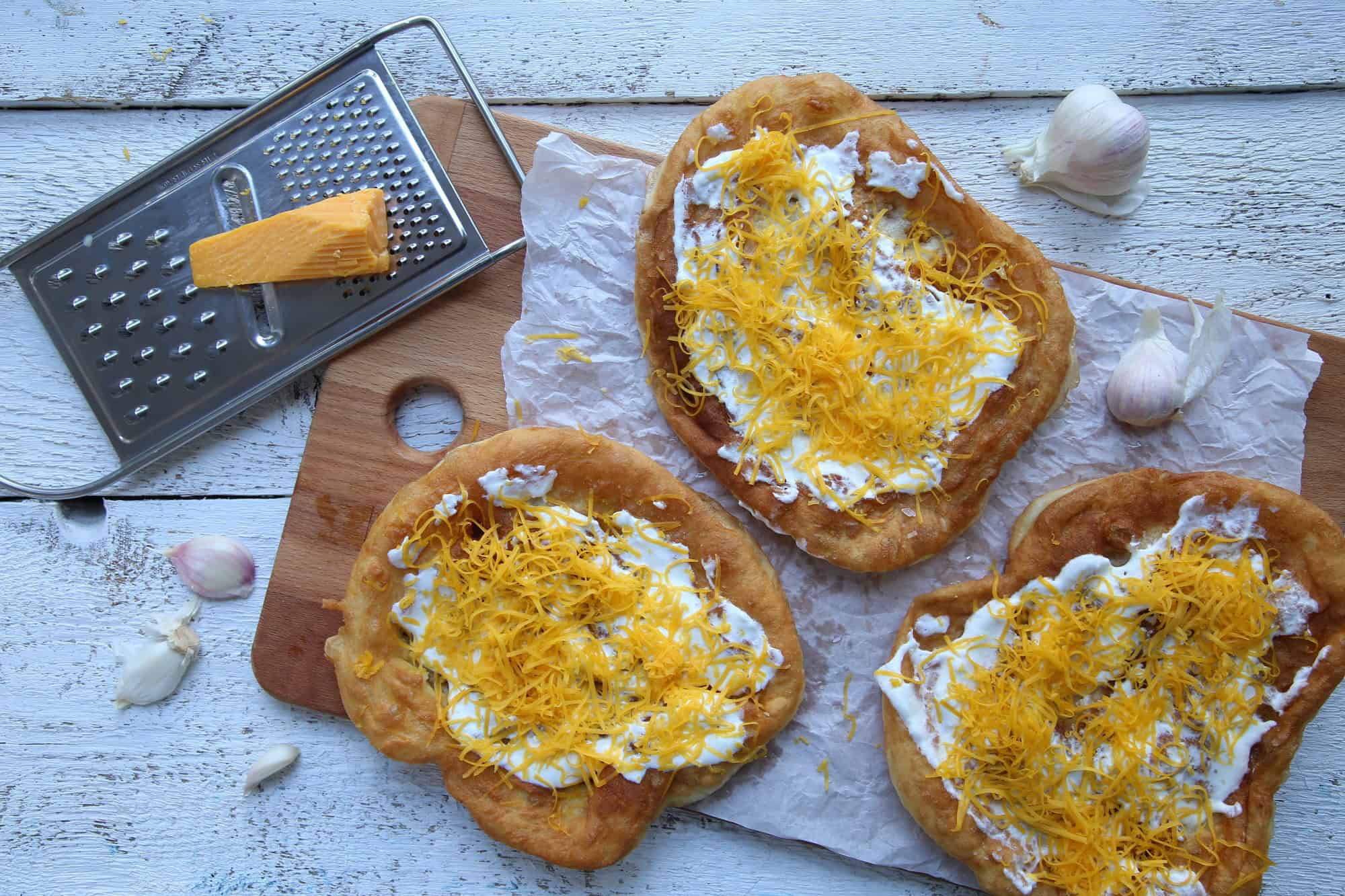 A classic Lángos topped generously with sour cream and shredded cheese