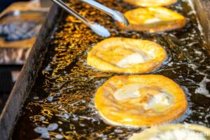A plain golden-brown fried lángos freshly brushed with traditional watery chopped raw garlic