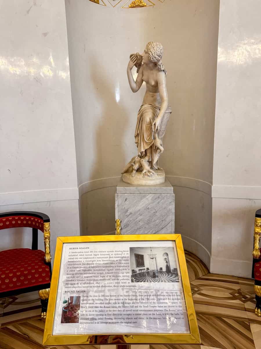 A white marble classical statue in a niche of the Round Salon