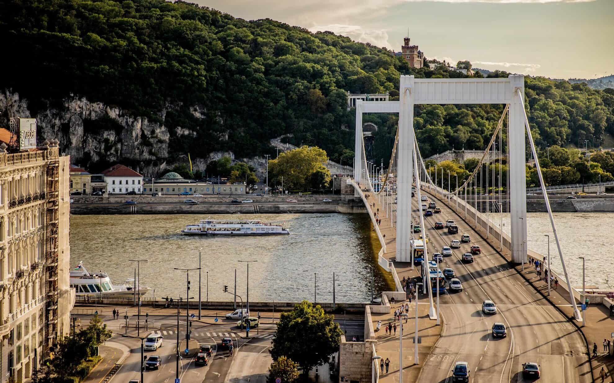 A vibrant cocktail on a rooftop bar table overlooking the illuminated Erzsébet Bridge at night