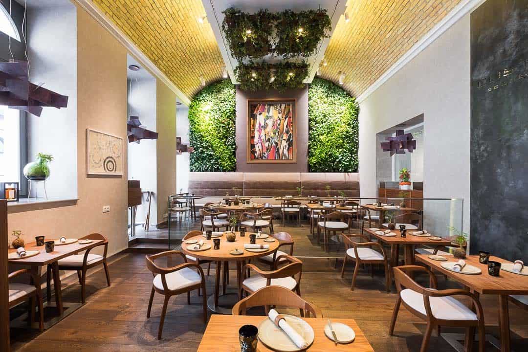 The luxurious dining room of the Michelin-starred Costes Downtown restaurant in Budapest, showing living green walls and modern decor.