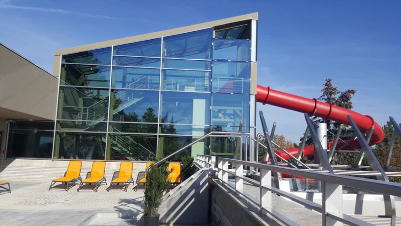 Colorful outdoor summer water slides winding down a grassy hill at Csillaghegyi Bath