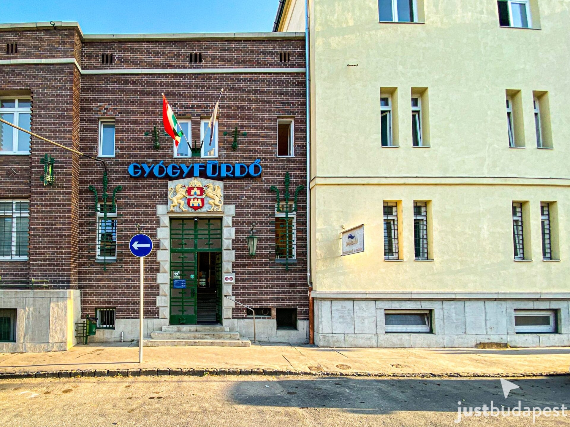 The modest brick exterior facade of the historic Dandár Bath building on a quiet street