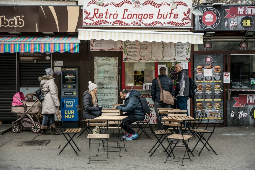 A street vendor carefully flipping a large disc of puffed dough in a vat of boiling cooking oil