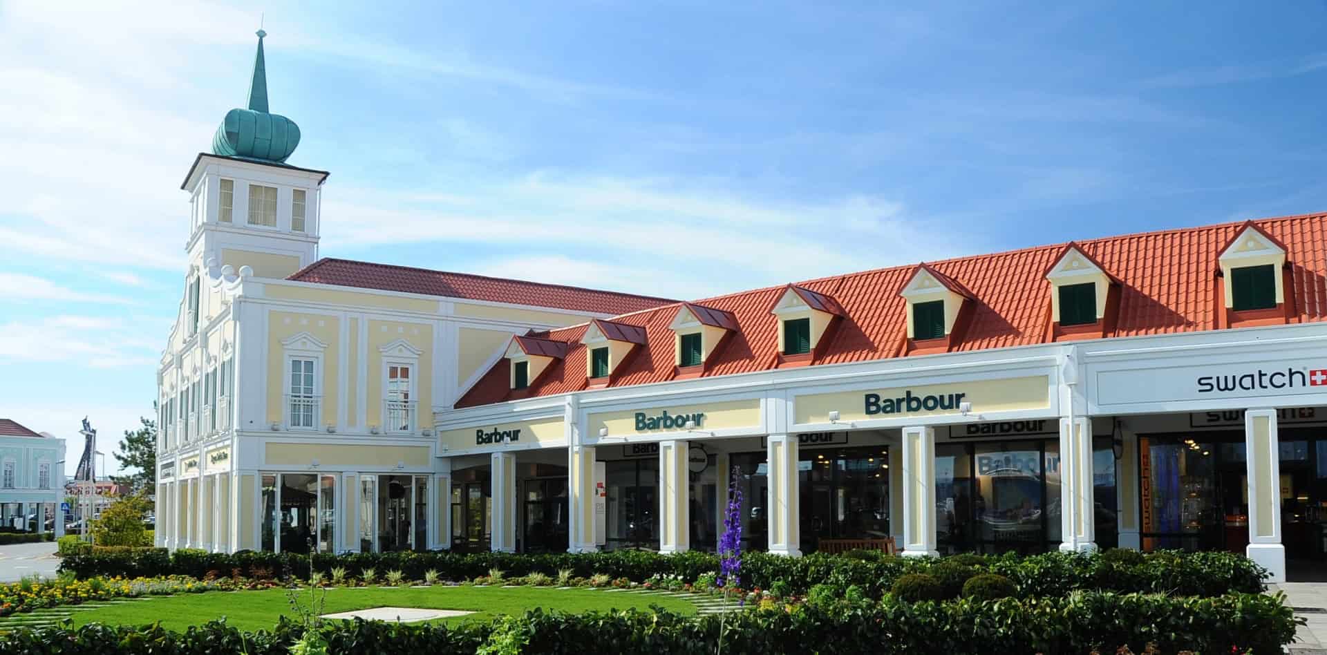 People walking and shopping inside the open-air village complex of Designer Outlet Parndorf