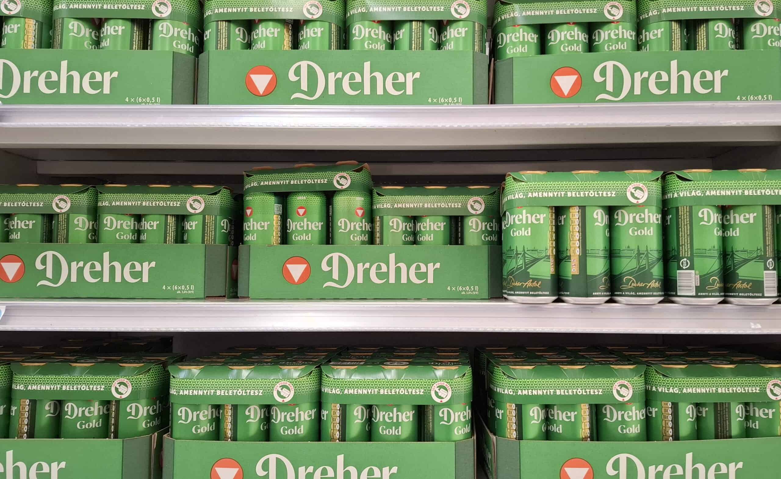 Rows of green Dreher Gold beer cans on the shelves of a Hungarian supermarket.