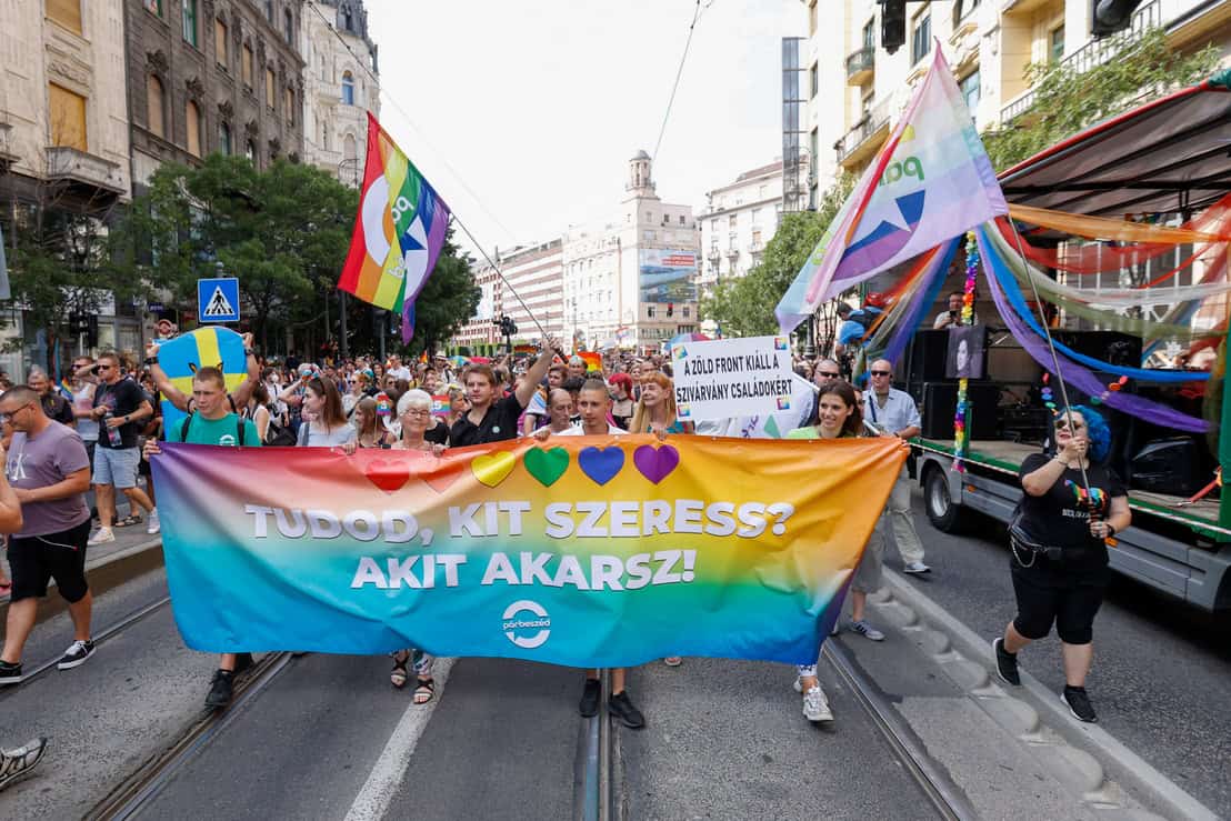 A group holding a rainbow flag featuring European Union stars and a central heart