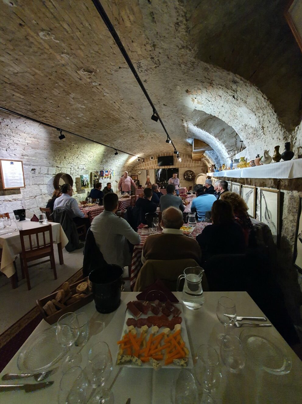 A sommelier guiding a wine tasting in a historic underground cellar
