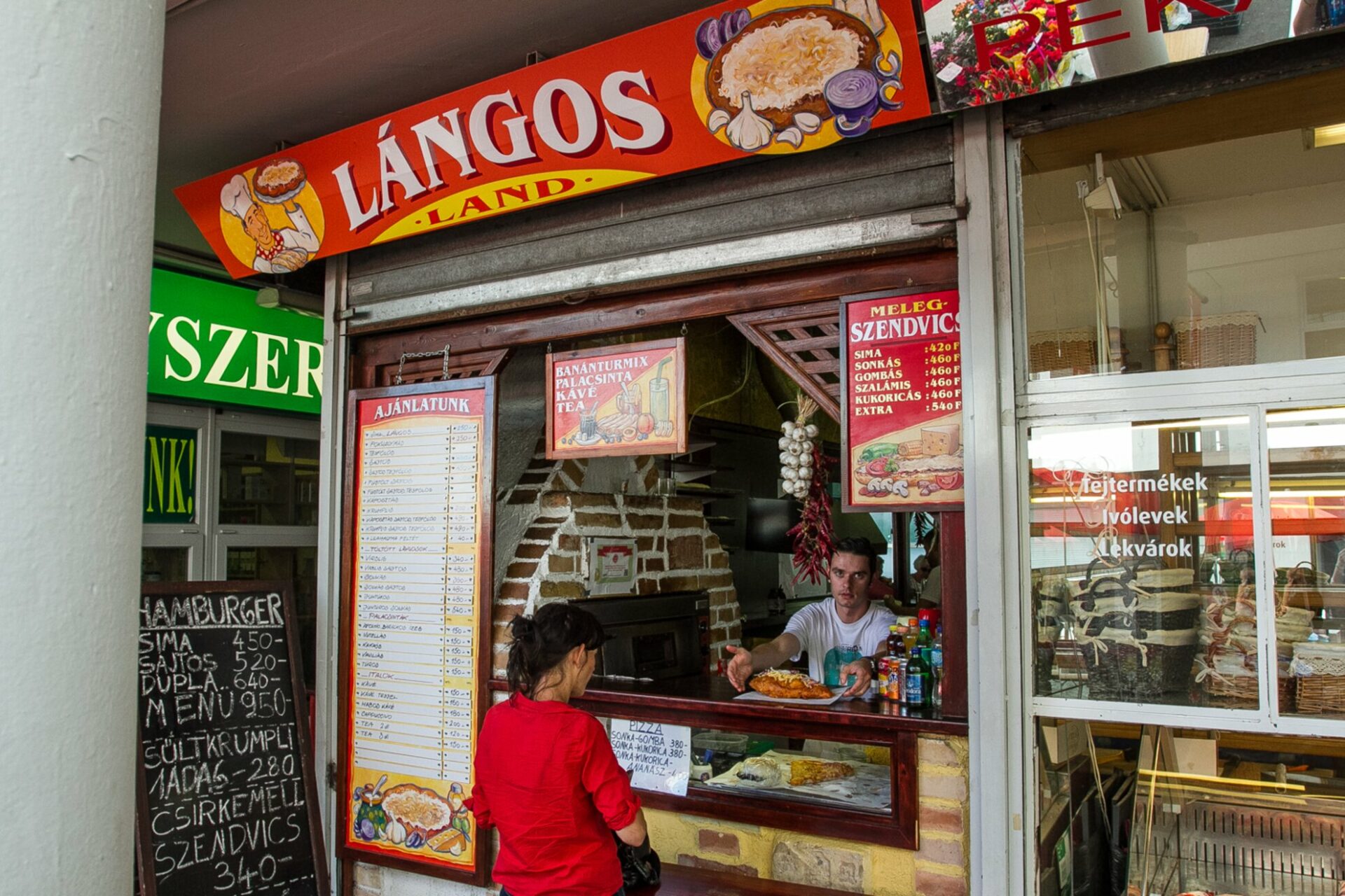 Locals lining up at a specialized lángos vendor inside the busy Fény Street Market hall