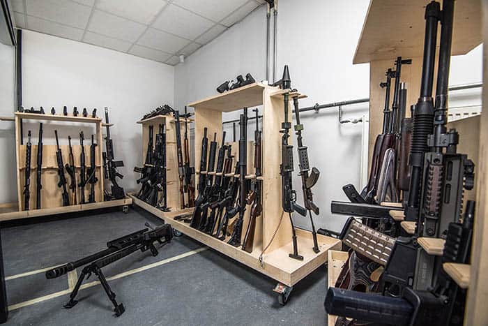 Wooden armament racks filled with modern assault rifles and tactical shotguns