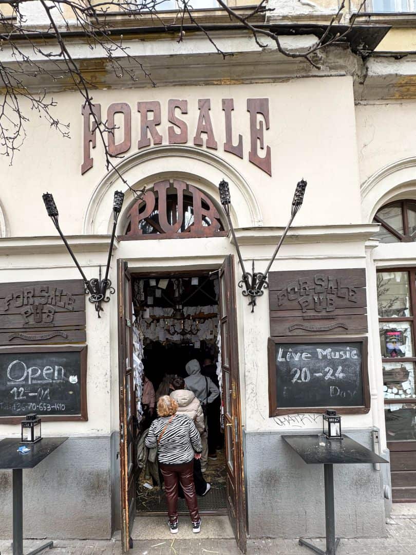 The rustic, wood-covered exterior facade and entrance of the For Sale Pub in Budapest
