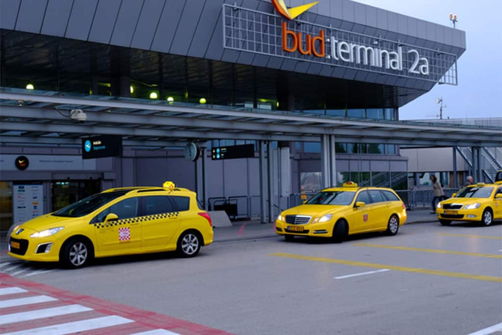 The official Főtaxi booking kiosk sitting outside the airport terminal doors