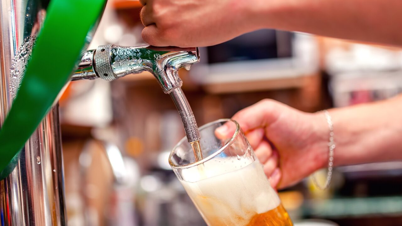 A group of friends happily raising large pints of beer inside a Budapest pub