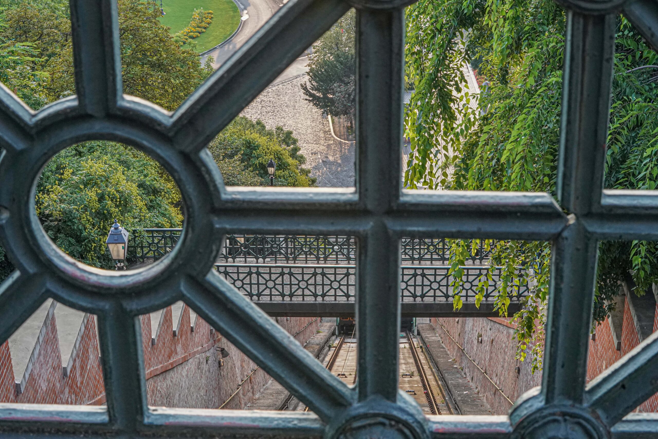 Artistic framed view of the funicular tracks through an ornate iron grille