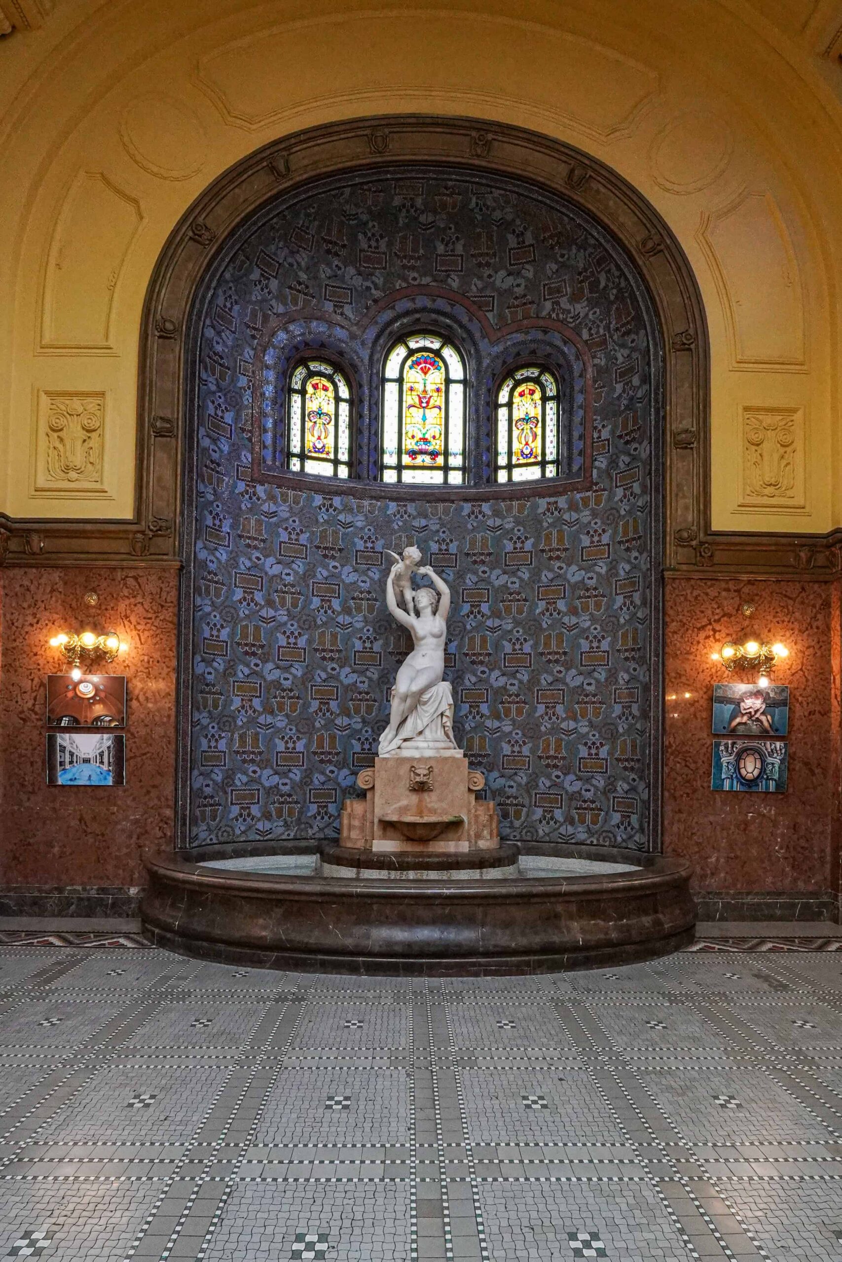 A classical bronze statue and incredibly detailed stained-glass window in the Gellért lobby