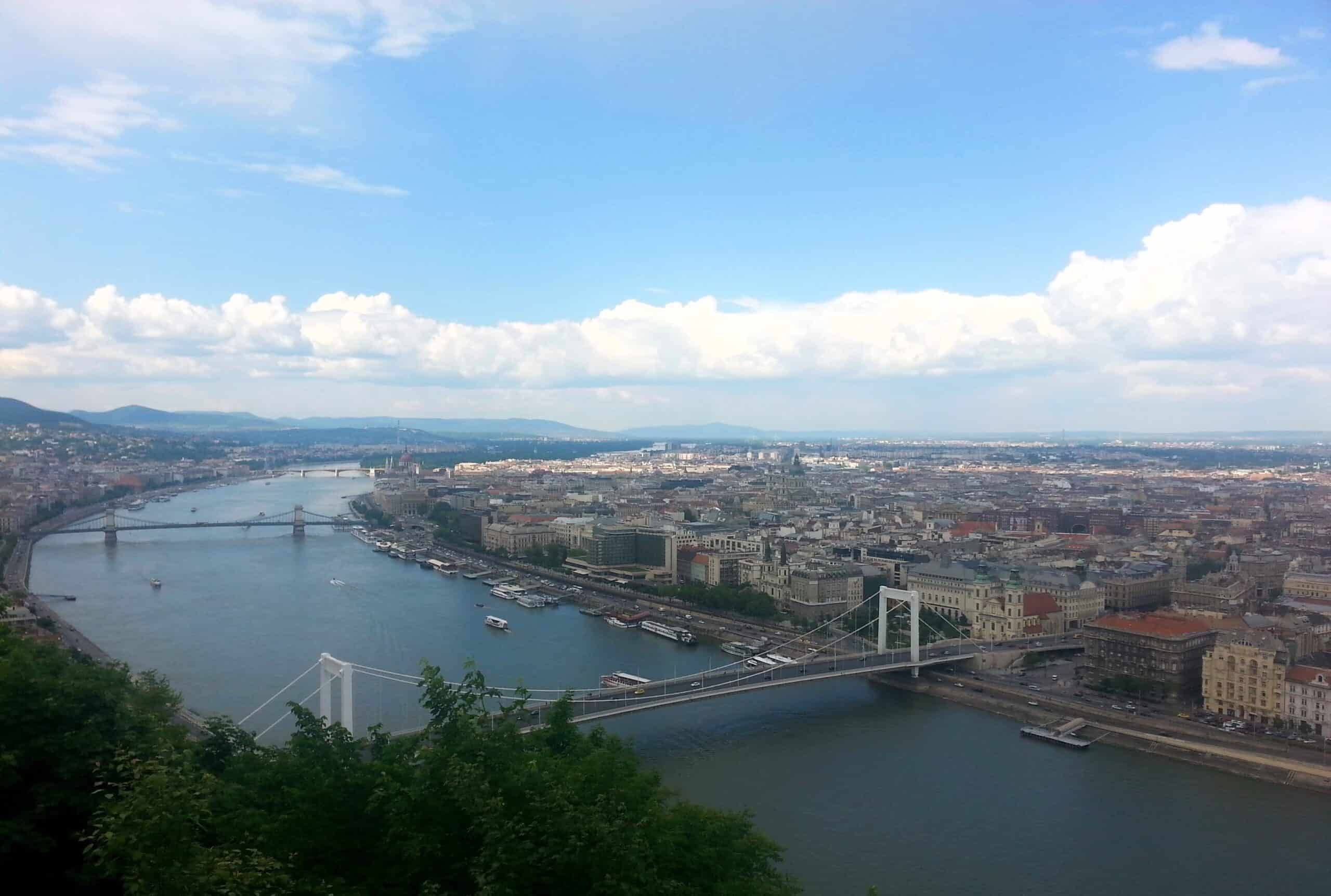 An exceptionally wide panorama shot from Gellért Hill showcasing the major bridges curving along the river