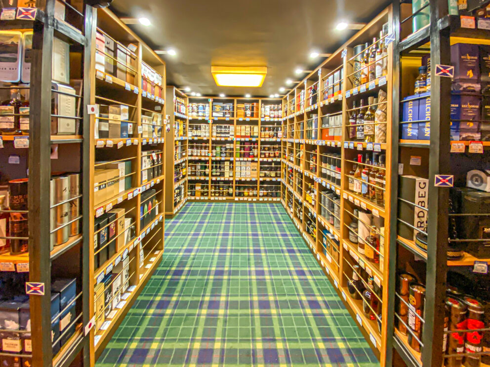 Immaculately organized wooden retail display cases filled with high-end single malt whiskies