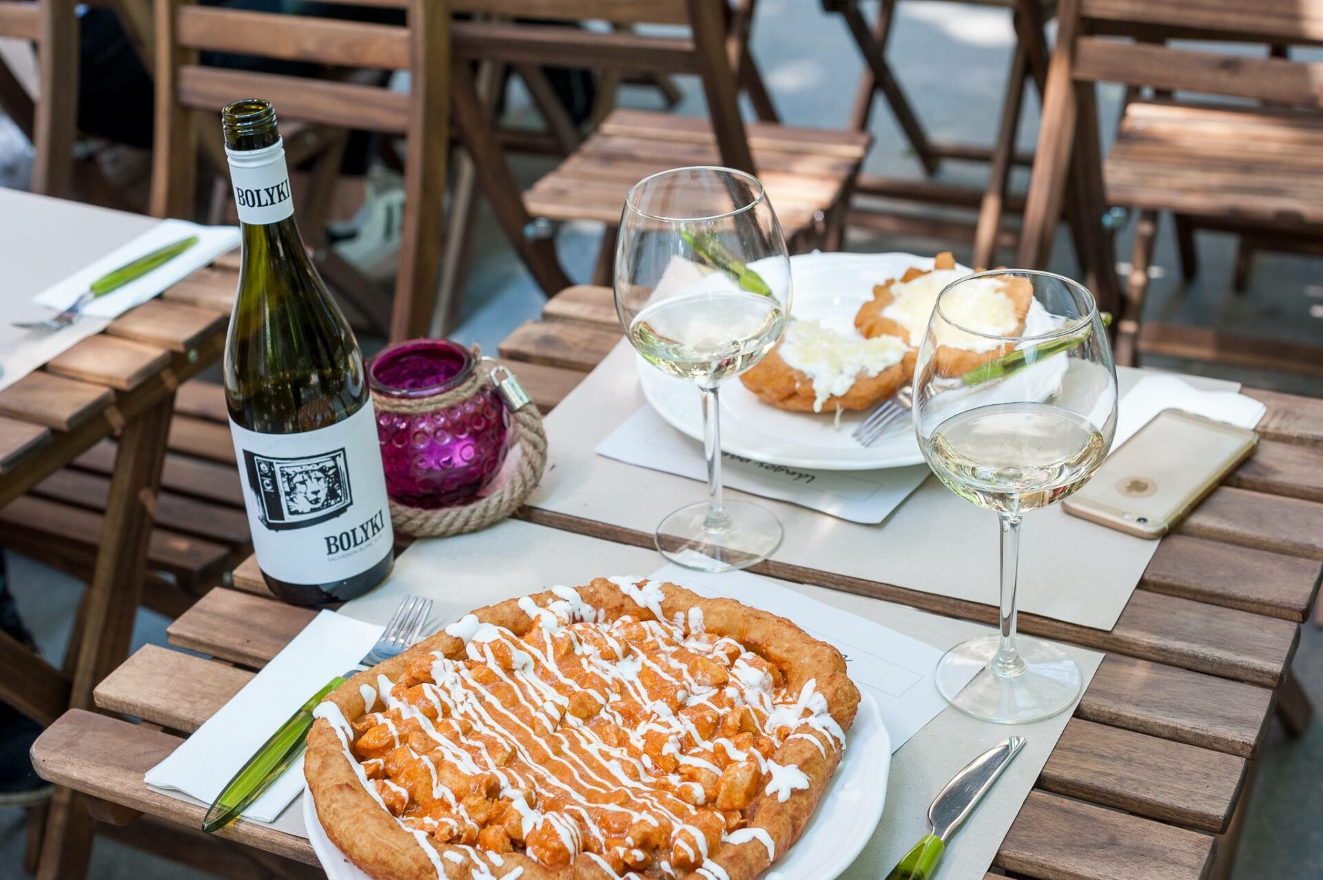 A vibrant gourmet lángos heavily loaded with non-traditional toppings like fresh arugula and meats