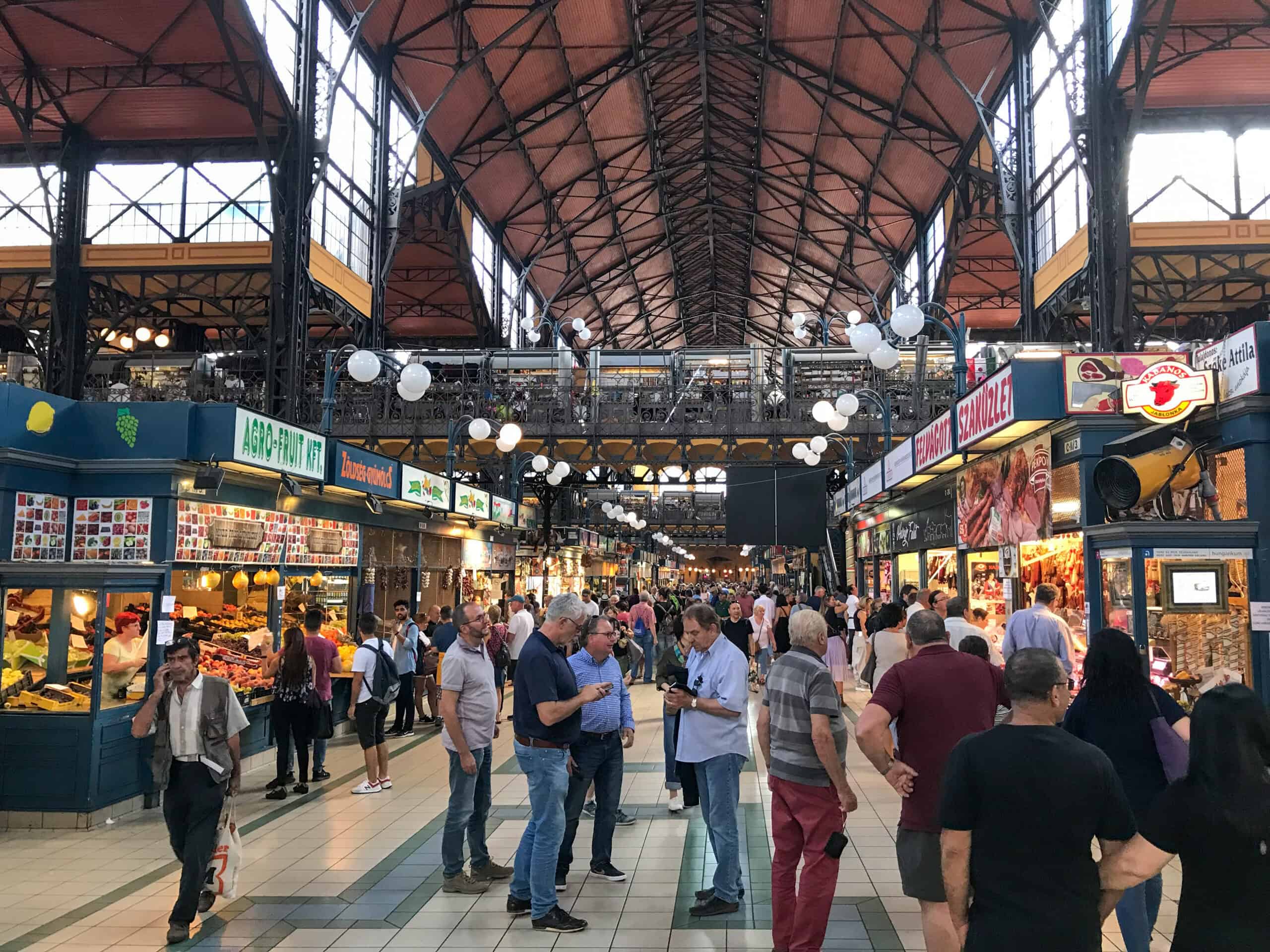 Looking down the main aisle of the Budapest Great Market Hall with its iconic steel structure and colorful food stalls.