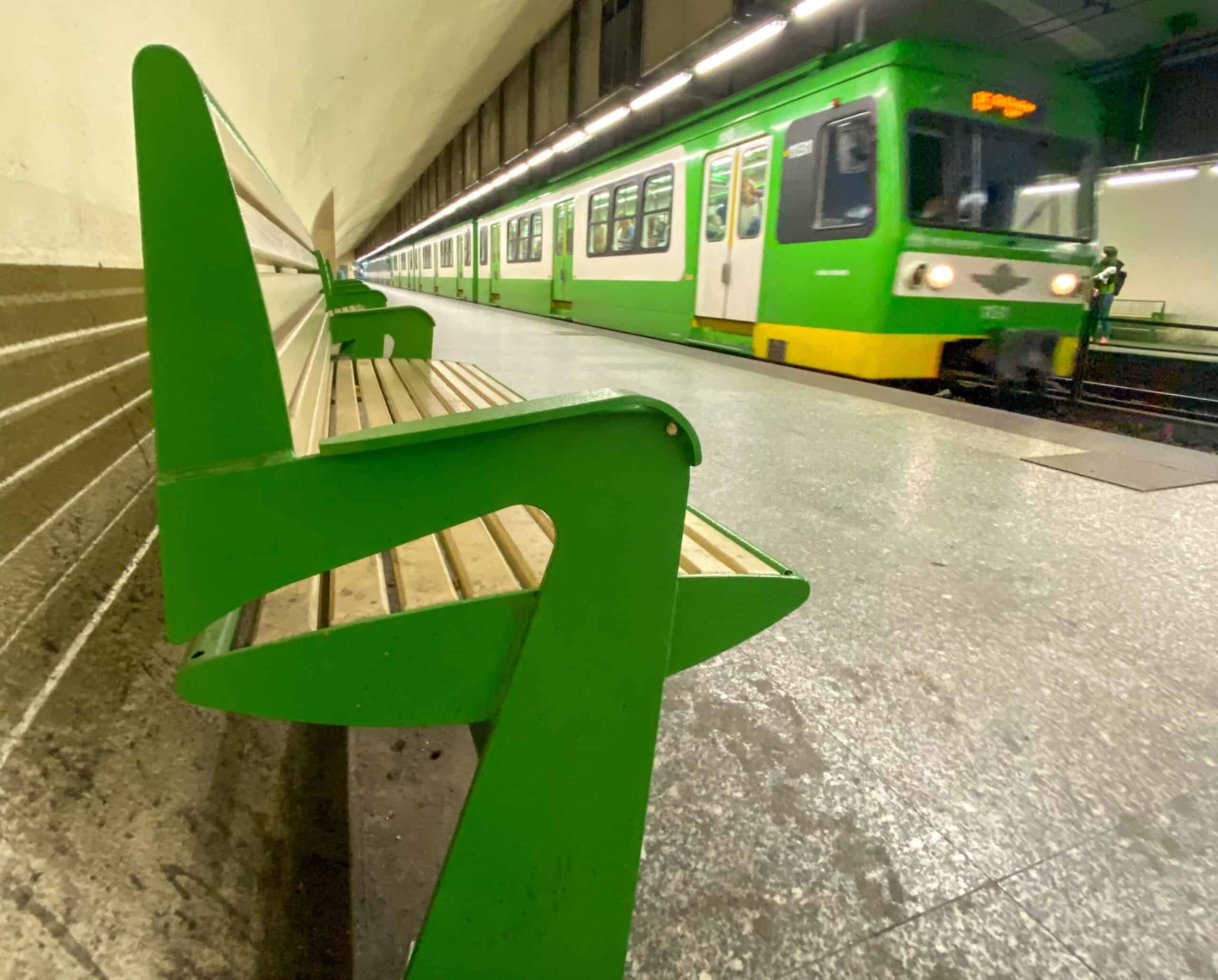 A green HÉV suburban train waiting at a platform in Budapest